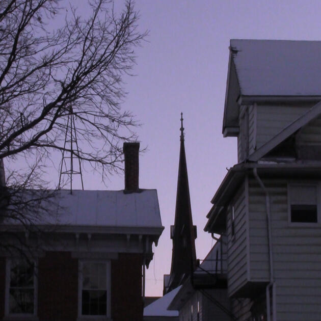 a photographic still from the short film Gender Euphoria which depicts a steeple poking up from the space between two houses